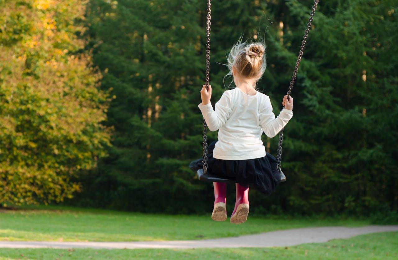 a child a swing facing away from the camera