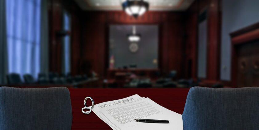 an empty courtroom in the background with a divorce agreement on a desk in the foreground