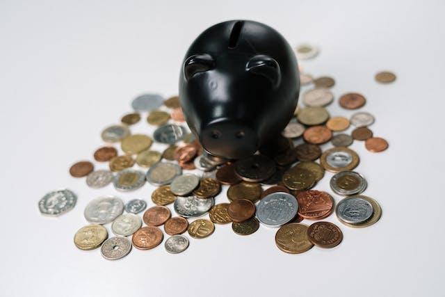 a black piggy bank on a pile of coins