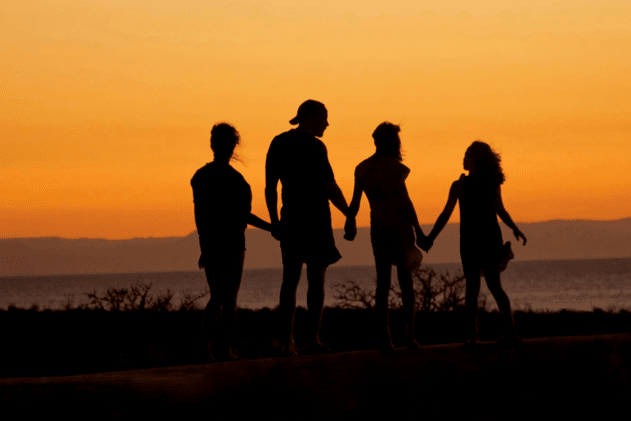 the silhouette of a family against an orange sunset
