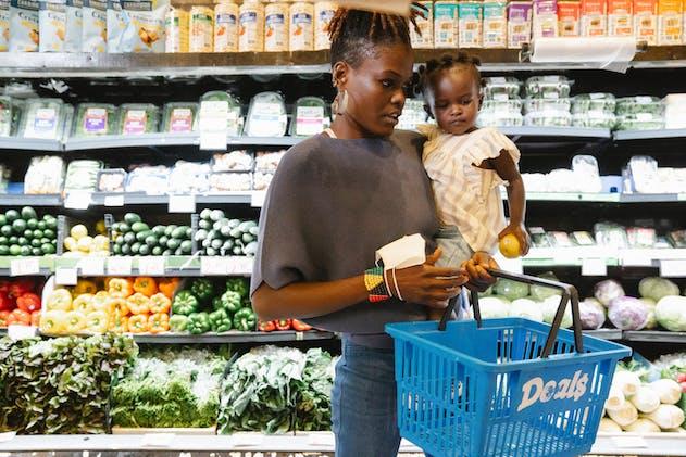a mom holding her child while shopping at the grocery store