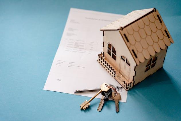 a model of a house and a pair of keys on top of a piece of paper