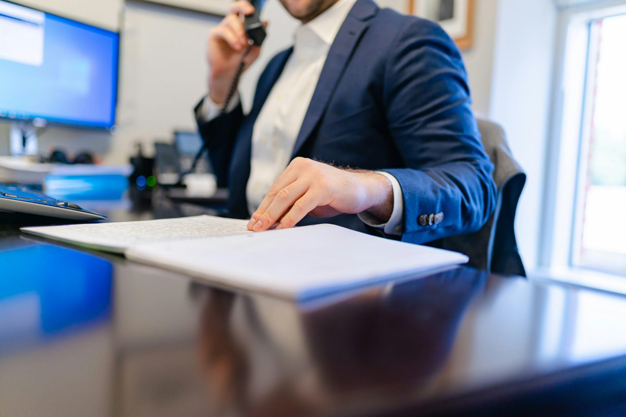 A man in a suit is engaged in a phone conversation, appearing focused and professional.