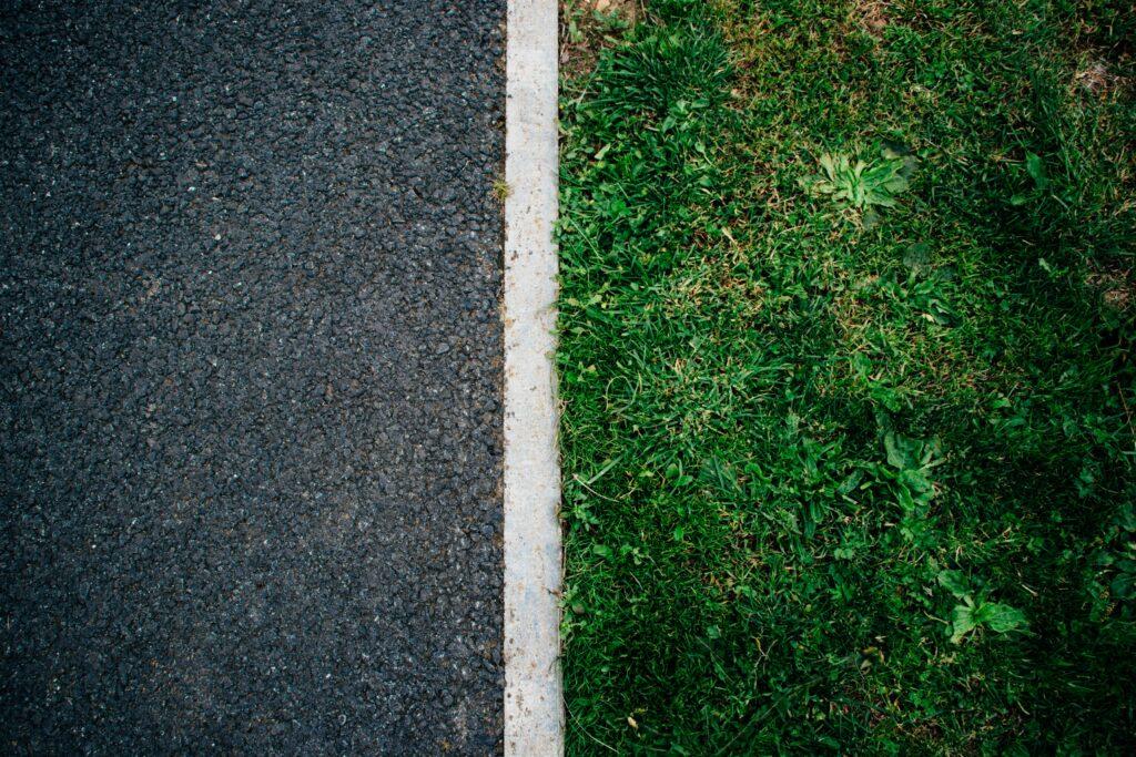 An asphalt road separated from a grassy patch by a painted white line